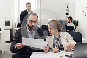 A young Manager gives paper documents to the head of the HR Department in the office of the leasing company for