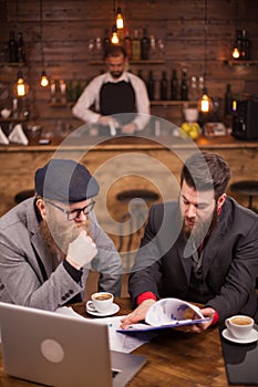 Young managers checking documents of his pub with barman blurred in the background