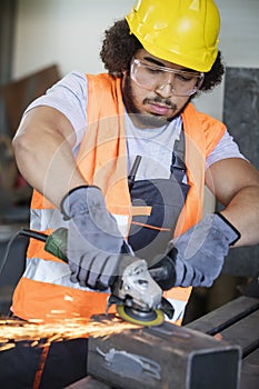 Young manual worker grinding metal in industry