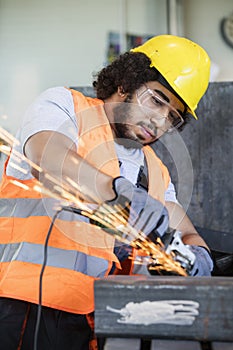 Young manual worker in protective workwear grinding metal in industry photo