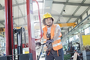 Young manual worker pushing hand truck in metal industry