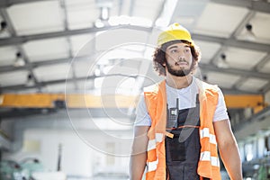 Young manual worker wearing protective clothing looking away in metal industry