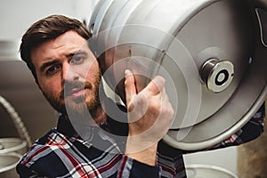 Young manufacturer carrying keg in brewery