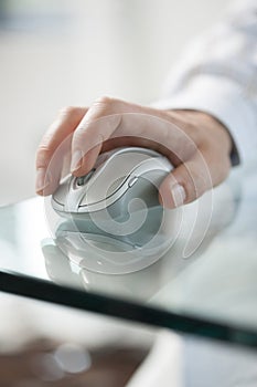 Young manâ€™s hand clicking on a cordless computer mouse on a gr