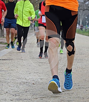 Young marathoner runs with athletic taping on the his knee durin