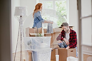 Young marriage packing stuff into boxes during relocation to new home