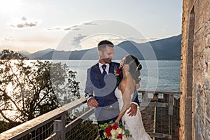 Young married couple on a balcony overlooking the lake in Torri del Benaco, Italy.