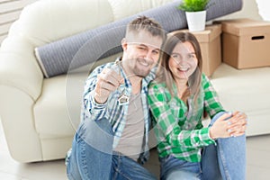 Young married couple with boxes and holding flat keys.