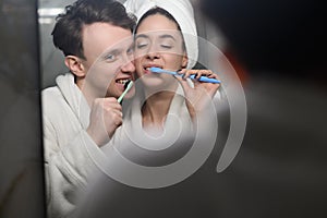 a young married couple brushing their teeth together. Dental hygiene.