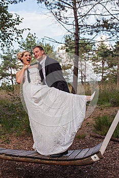 Young married couple is frivolous on a large swing. photo