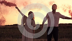 A young married couple holding coloured smoke in their hands