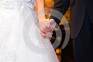 Young married couple holding hands, ceremony wedding day