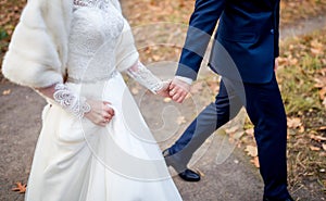 Young married couple holding hands, ceremony wedding day. Bride and groom outdoor. Closeup.