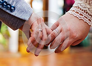 Young married couple holding hands, wedding ceremony. Newlyweds hands with wedding rings.