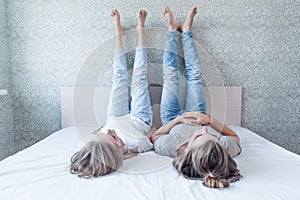 A young married couple lies on the bed, legs to the wall and looks at the ceiling, the relationship is paired