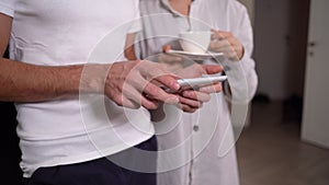 Young married couple in the morning at home in the kitchen, closeup male hands holding a tablet in their hands