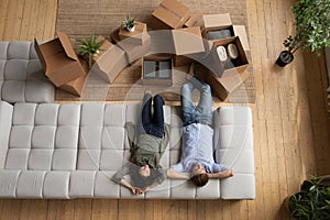 Young married couple rest on cozy couch after packing stuff