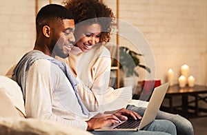 Young married couple using laptop at cozy winter evening