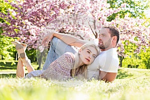 Young married people in love enjoying the spring beautiful nature. Beautiful young couple enjoying flowering garden. Man