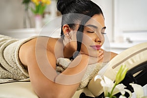 Young masseuse massaging pretty dark hair woman in spa salon