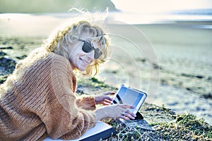 Young mature blonde woman relaxing outdoor with a tablet.