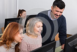 Young and mature business people grouped around computer monitor