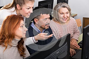 Young and mature business people grouped around computer monitor