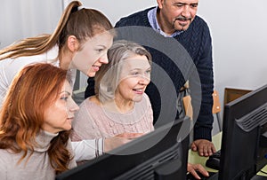Young and mature business people grouped around computer monitor