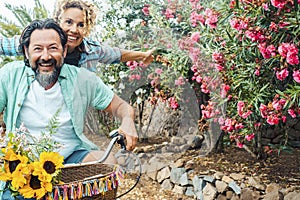 Young mature couple youthfully enjoy outdoor leisure activity together having fun and laughing. Man and woman riding a bike