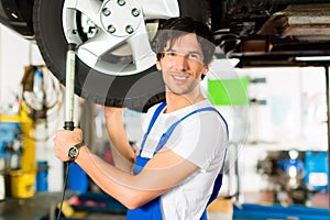 Young mechanic in blue overall working on car photo
