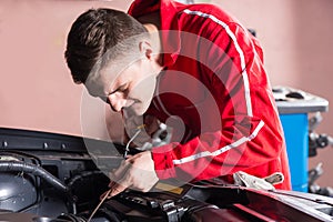 Young mechanic checking the oil level in a car engine