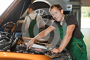 A young mechanic in green overalls is studying the cause of the