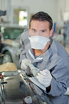 Young mechanic polishing bodywork