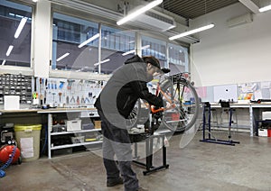 Young mechanic repairing the wheel of the bicycle inside the mec