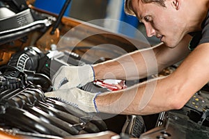 Young mechanic repairs the car engine