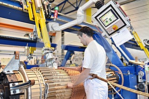 young mechanical engineering workers operate a machine for winding copper wire - manufacture of transformers in a factory