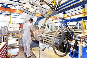 young mechanical engineering workers operate a machine for winding copper wire - manufacture of transformers in a factory