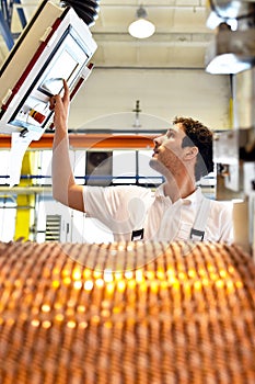 young mechanical engineering workers operate a machine for winding copper wire - manufacture of transformers in a factory