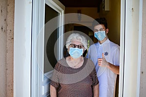 Young medic helping and old eldery woman to walk wear mask covid19 photo