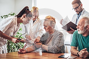 Young medic taking blood pressure during home visit