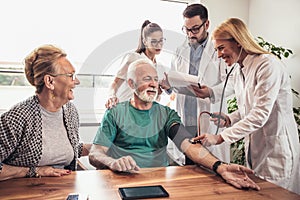 Young medic taking blood pressure during home visit