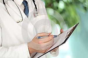 Young medical doctor with a stethoscope around his neck holdi