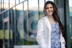 Young medical professional at her new career job, standing portrait in a white coat