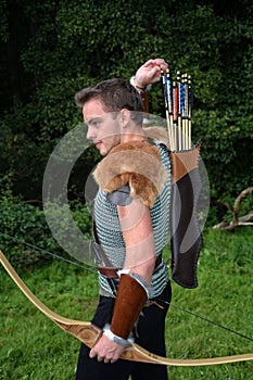 Young Medieval archer with chain shirt reaches for arrow, with bow in hand