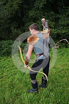 Young Medieval archer with chain shirt reaches for arrow, with bow in hand