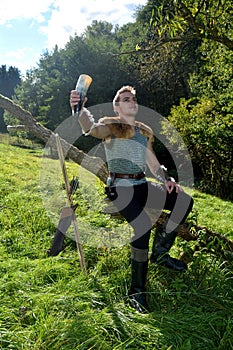 Young Medieval dressed man, holds drinking horn high in the hand, looks upwards