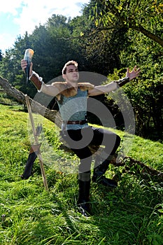 Young Medieval dressed one man, holds drinking horn in hand, both arms stretched out