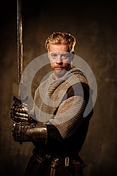 Young medieval knight posing on dark background. photo