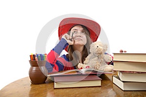 Young meditative girl with red hat and her teddy bear at the table