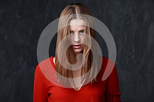 Young melancholic woman in red dress, face is partly closed by t